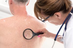 Dermatologist examining the skin on the back of a patient